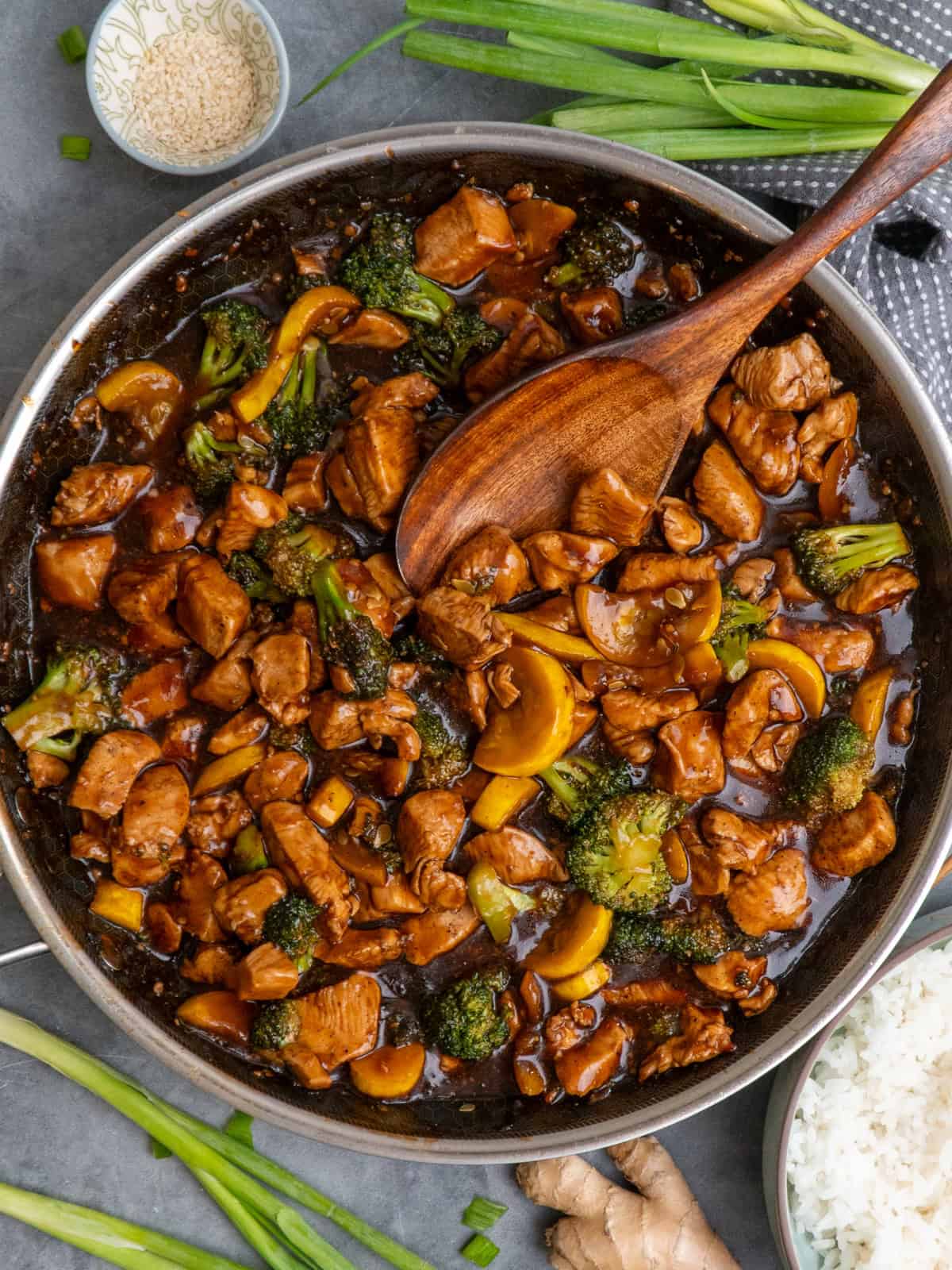Teriyaki chicken and broccoli in a skillet with a wooden spoon ready to be served.