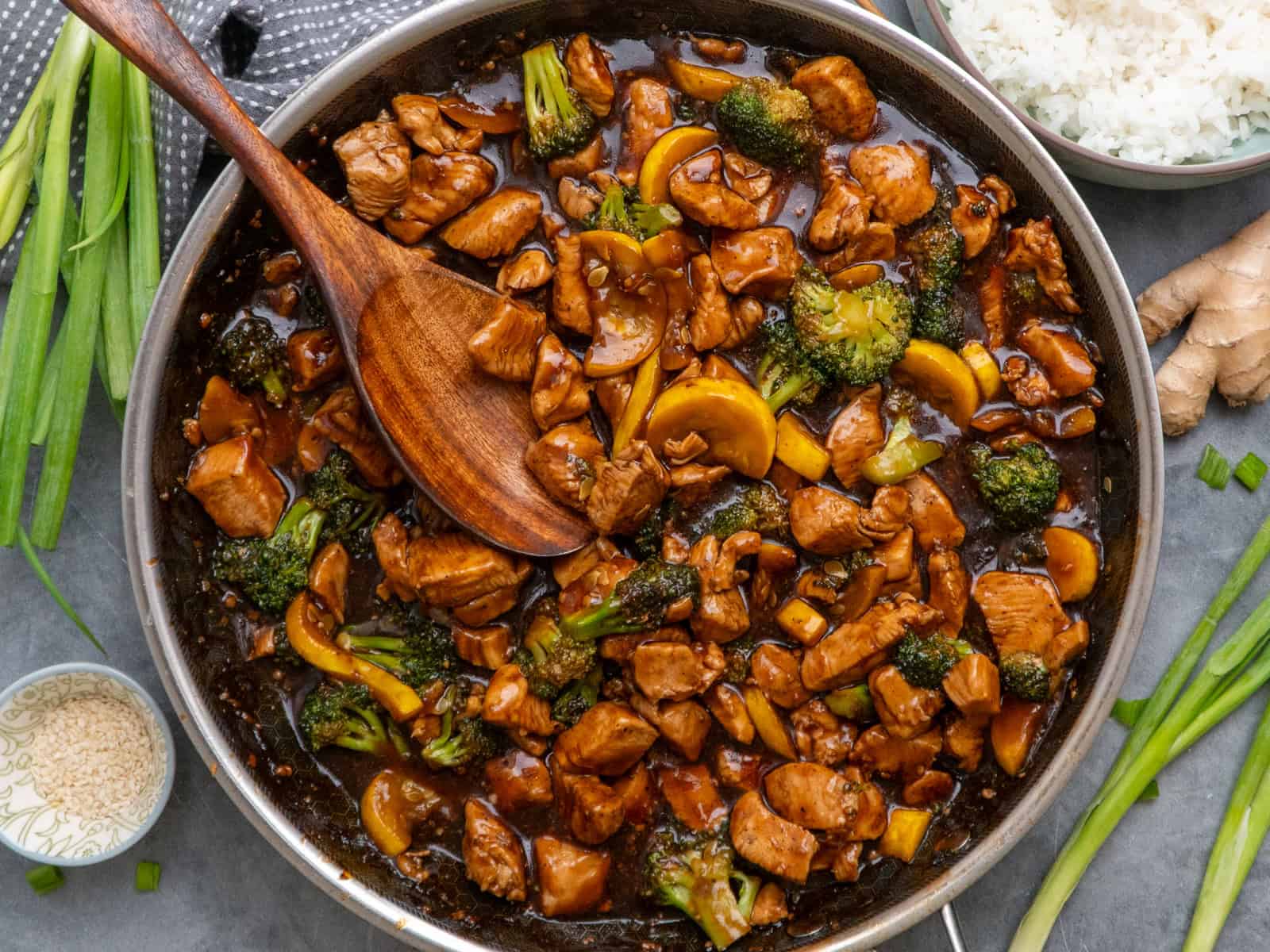 Teriyaki chicken and broccoli in a skillet with a wooden spoon ready to be served.